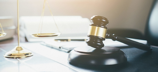 A gavel and scales are on a desk.
